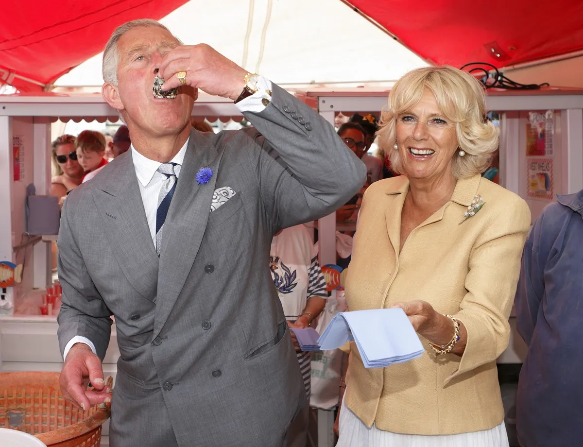 King Charles eats a oyster as he and Camilla Parker Bowles visit the Whitstable Oyster Festival